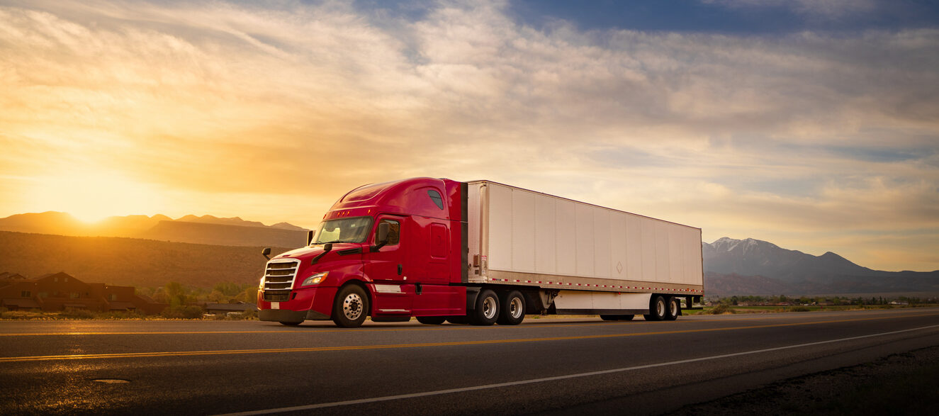 Red and white semi-truck speeding at sunrise on a single lane road USA