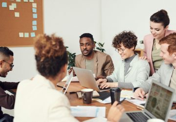Technology professionals collaborating around table with laptops demonstrating face-to-face networking benefits emphasized in IBM i user groups