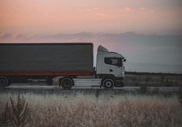 White semi truck with dark trailer parked in field at dusk representing digital age trucking and real-time data processing